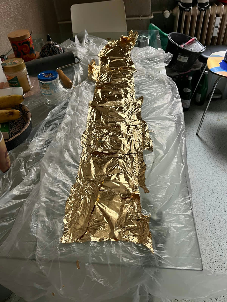 Einzelne Blattgoldblätter liegen locker auf einer vorbereiteten Fläche