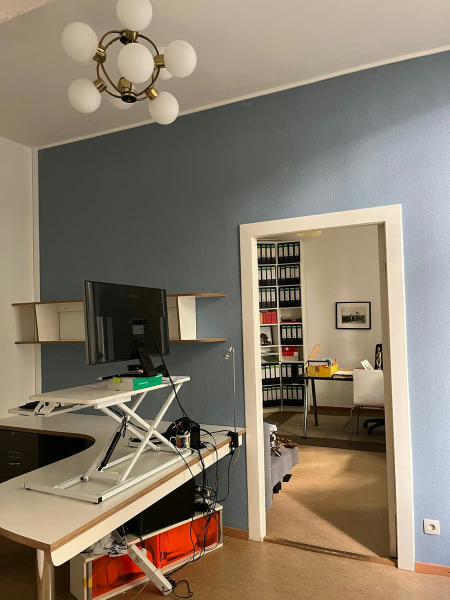 Der fertige Kanzleiraum mit blaugrau abgesetzter Wand, Schreibtisch und Durchgang zum Aktenraum