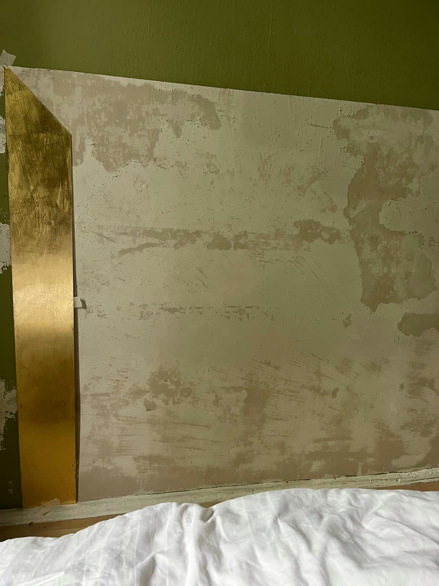 Das fertig angelegte Kopfteil ist an der Wand angebracht, die erste vergoldete Leiste sitzt bereits an der linken Kante