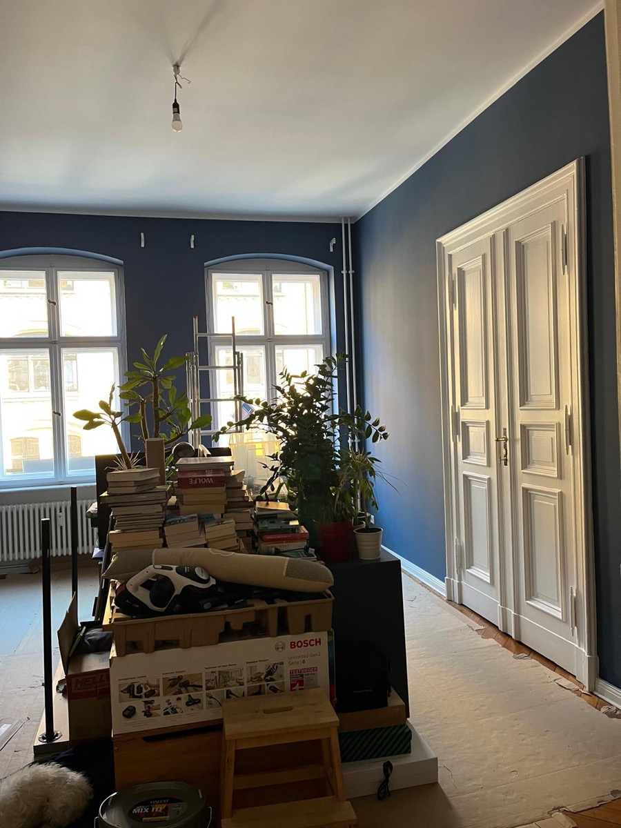 Derselbe Raum fertig gestrichen in tiefem Blaugrau, mit weiß abgesetzten Altbautüren und Fensterrahmen
