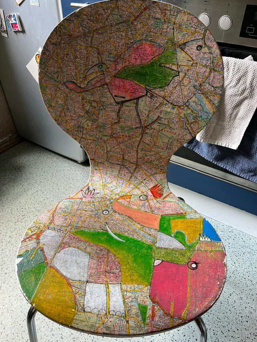 Bemalter Stuhl, beklebt mit Berliner Stadtplänen und farbig überarbeiteten Tierfiguren