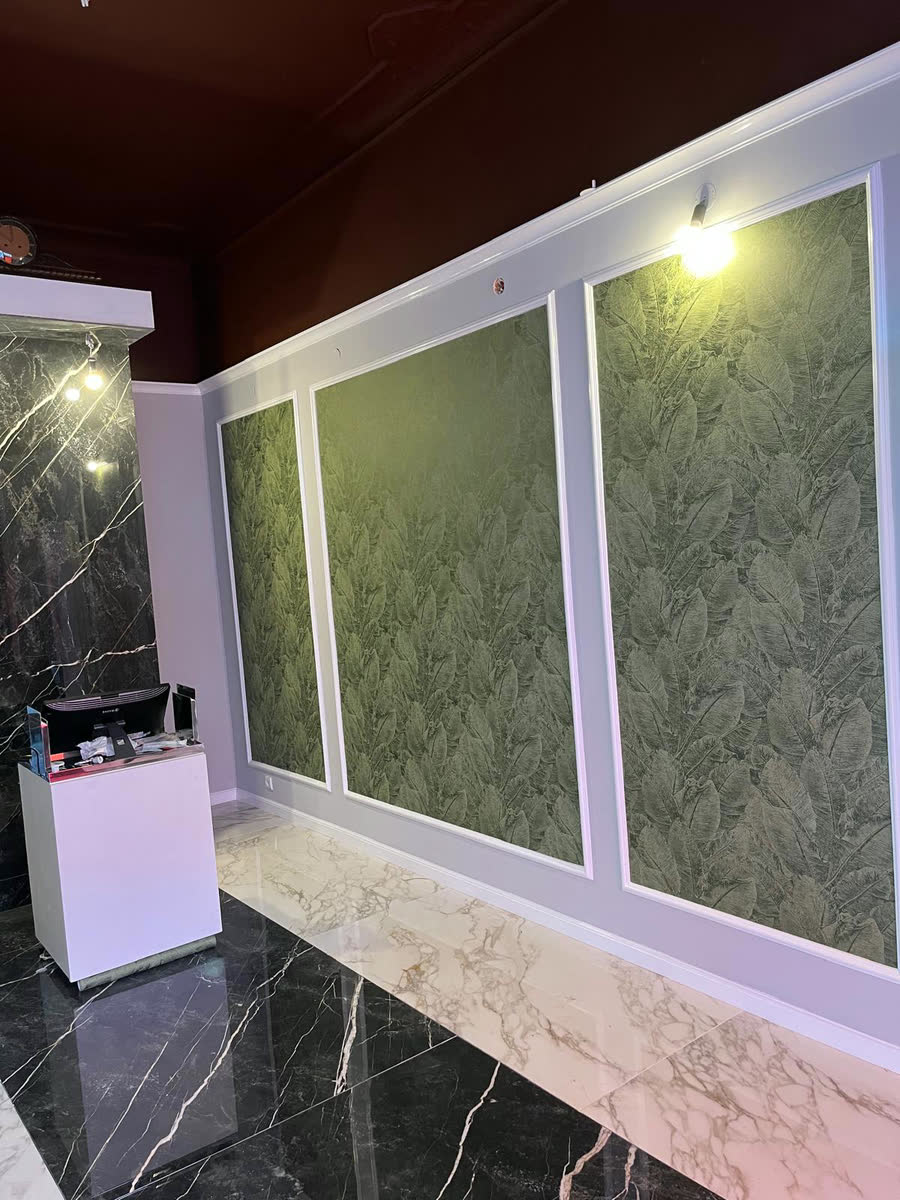 Fertige Wand mit botanischer Tapete, in weiße Rahmenfelder gefasst, über einem Marmorboden und unter weinrotem Deckenspiegel