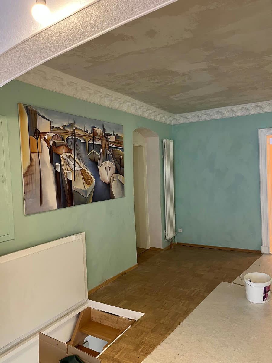 Wohnraum mit salbeigrüner Wand und großformatigem Gemälde, die Decke freigelegt und frisch gespachtelt
